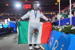 Marco Verde con la bandera mexicana tras colgarse la presea de plata.